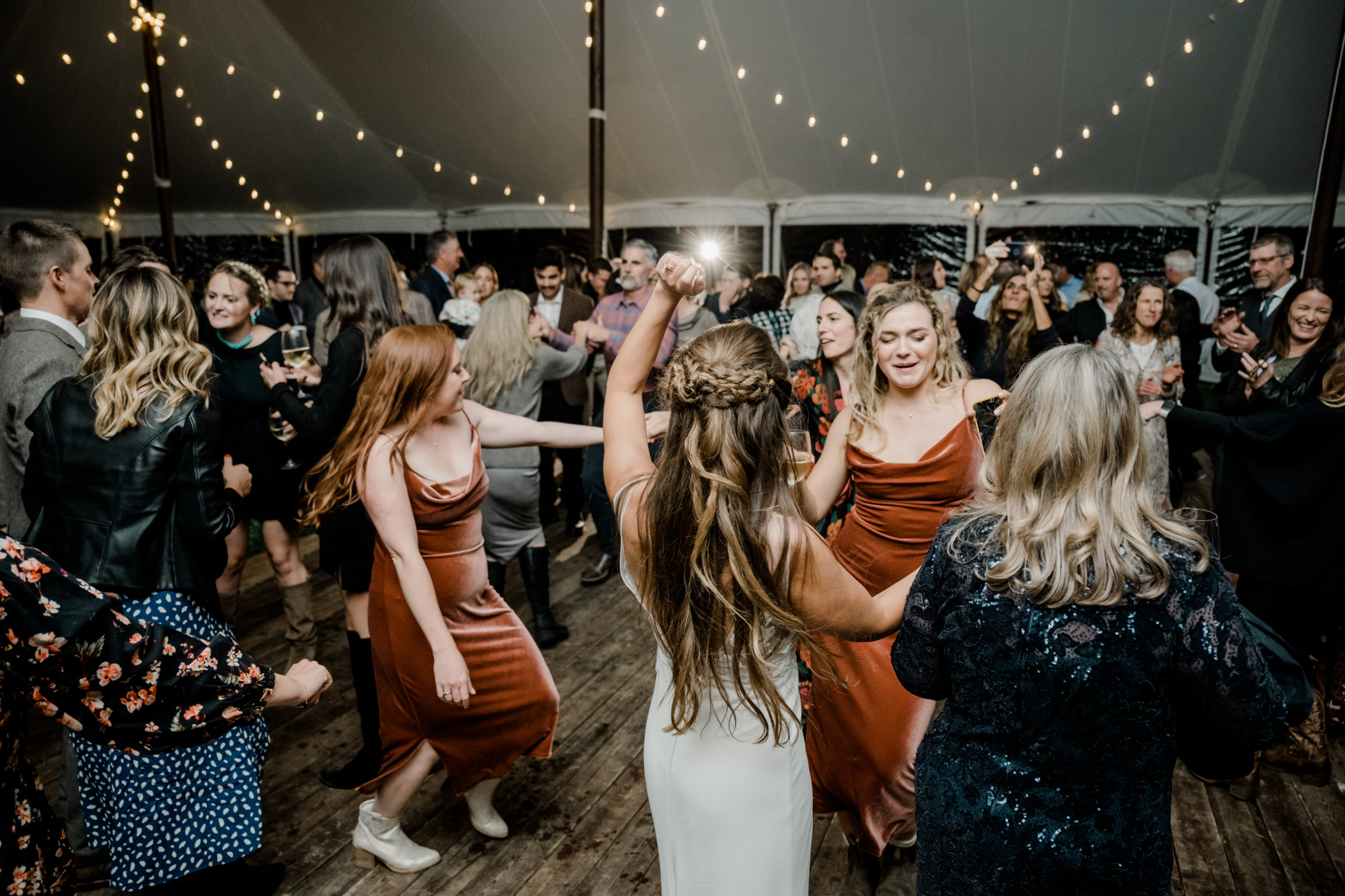 Bride and her bridesmaids dancing together on the dance floor.